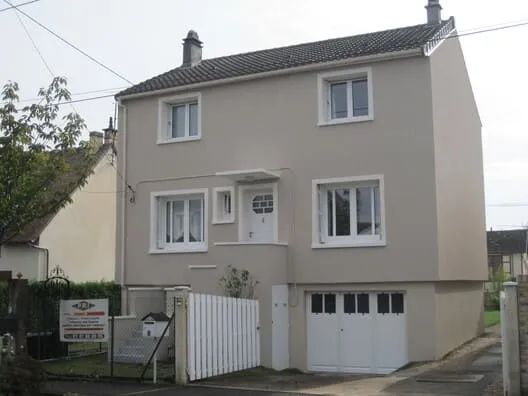 Façade de maison avec des fissures et des éclats avant rénovation.